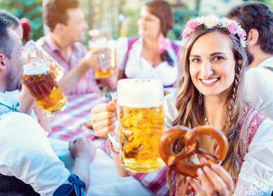 Frau toastet mit Glas Bier in bayerischer Kneipe in die Kamera  | © Gettyimages.com/kzenon