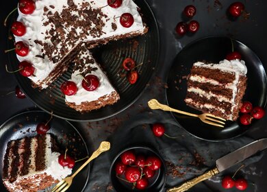 Bild von geschnittener Schwarzwälder Kirschtorte mit Pipetten mit Schlagsahnerosetten mit Morello-Kirschen, Luxus-Schokoladenkuchen mit Schlagsahne mattiert und mit Schokoladenspaenen ueberzogen | © Gettyimages.com/mtreasure