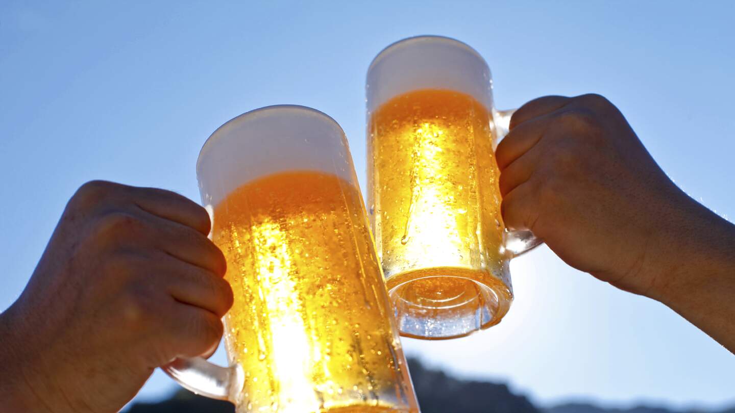 Untersicht auf zwei Hände die mit Biergläsern bei guten Wetter anstoßen | © Gettyimages.com/kazoka30