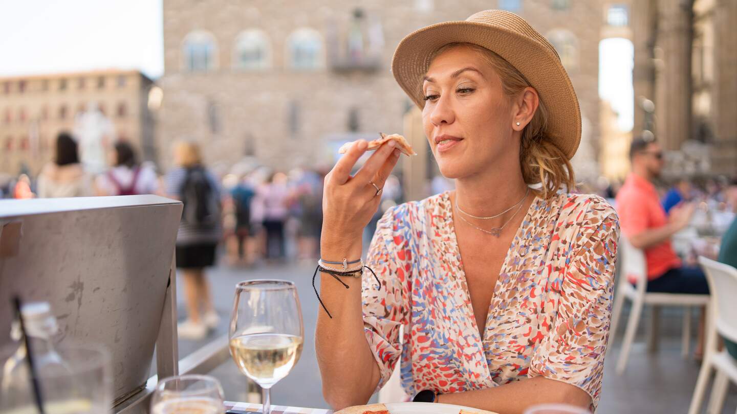 Frau probiert Pizza in einem italienischen Restaurant im Freien | © Gettyimages.com/	valentinrussanov