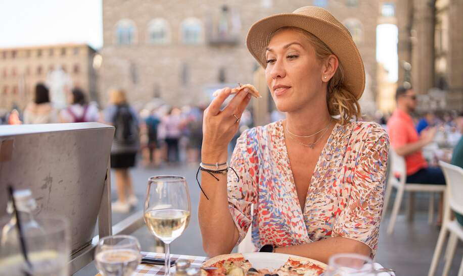 Frau probiert Pizza in einem italienischen Restaurant im Freien | © Gettyimages.com/	valentinrussanov