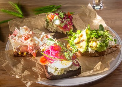 Traditionelle dänische Sandwiches, Smorrebrod mit gesalzenem Lachs, eingelegten Zwiebeln, Gemüse, grünen Erbsen und Speck  | © GettyImages.com/Milanchikov