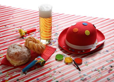 Karneval-Tisch mit Kölsch, Berliner und Karnevalshut in Köln | © Gettyimages.com/Maartje van Caspel