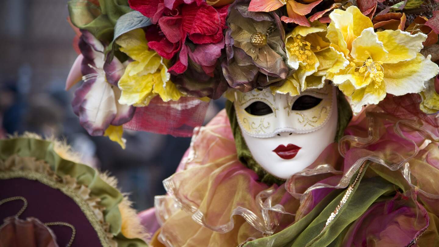 Frau in venezianischer Karnevals Verkleidung, mit Maske, pompoesem Blumenkopfschmuck und vielen Rueschen | © GettyImages.com/t-lorien