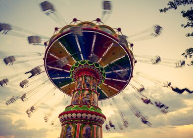 Die Leute amüsieren sich im Freizeitpark auf dem Kettenkarussell | © Gettyimages.com/yigitdenizozdemir