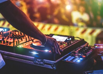 Dj Mixing Outdoor beim Silvester-Partyfestival mit Menschenmassen im Hintergrund | © Gettyimages.com/disobeyart