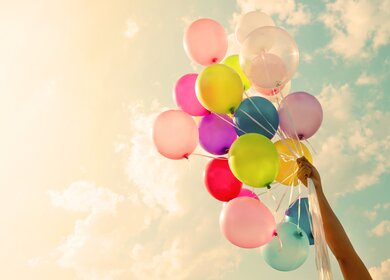 Maedchenhand, die bunte Luftballons haelt. | © gettyimages.com/jakkapan21
