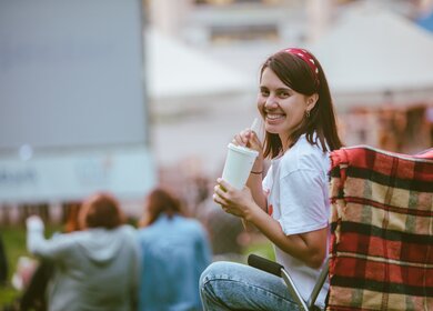 Frau sitzt im Campingstuhl und schaut Film im Open-Air-Kino | © Gettyimages.com/Vera_Petrunina