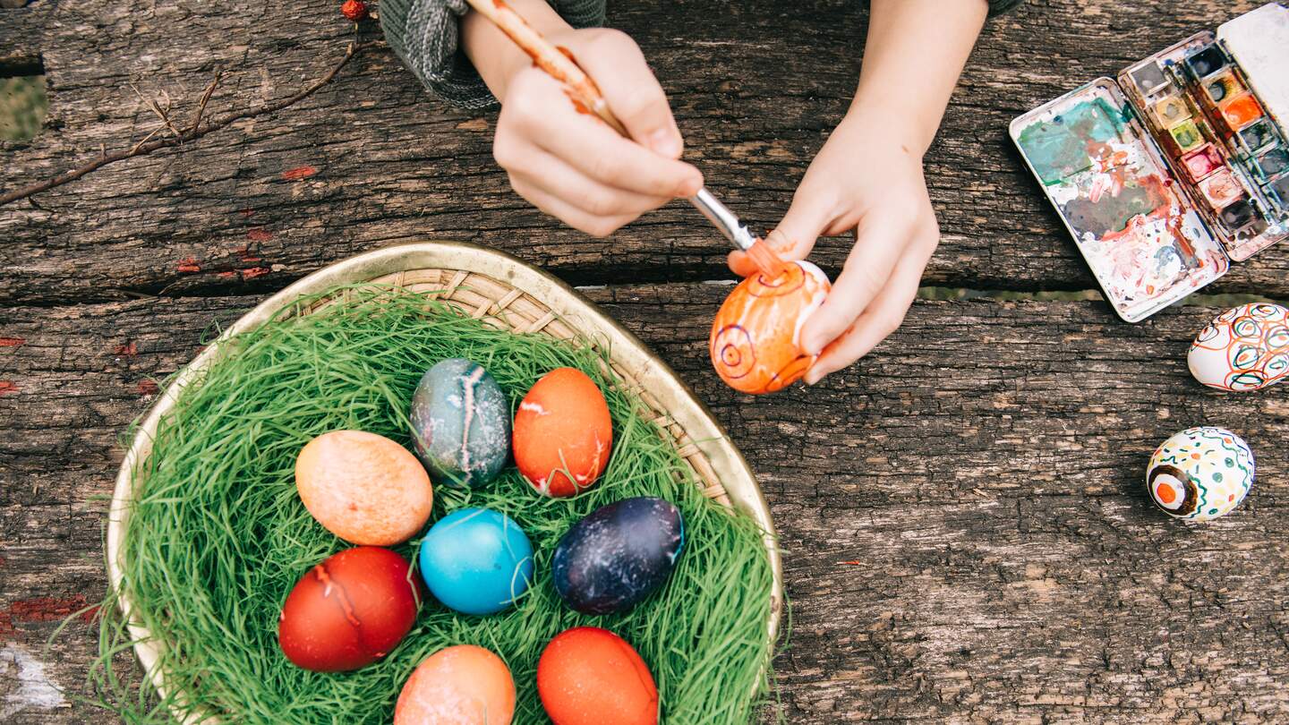 Ansicht von oben auf handbemalte Ostereier auf altem Holztisch mit roter Wasserfarbe | ©  Gettyimages.com/golero