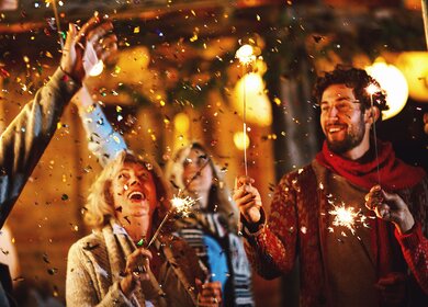 Eine Familie tanzt und feiert Silvester im Freien. | © Gettyimages.com/AjaKoska