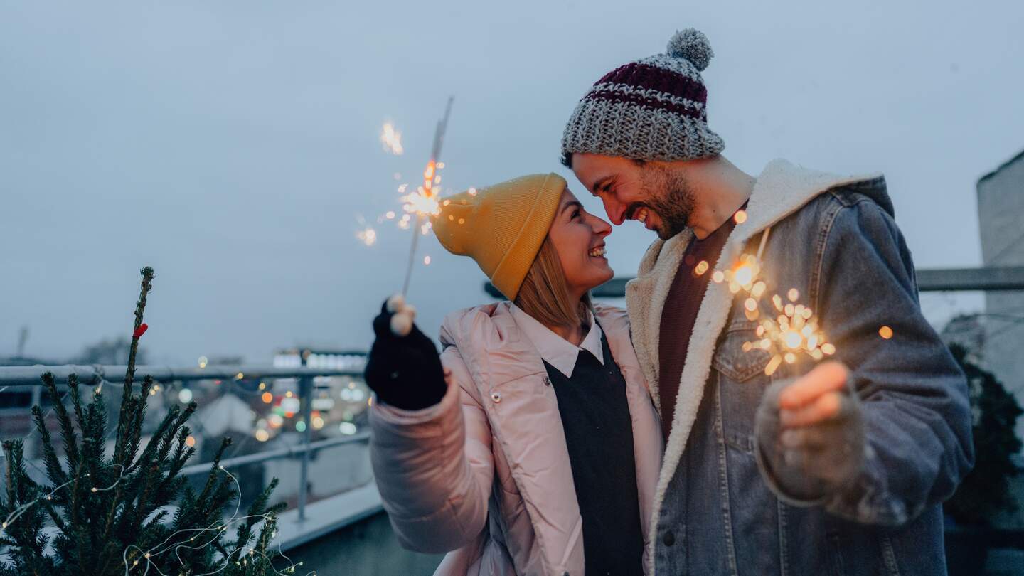 Junges Paar mit Wunderkerzen, die die schneereiche Silvesternacht zusammen geniessen. | ©  Gettyimages.com/AleksandarNakic