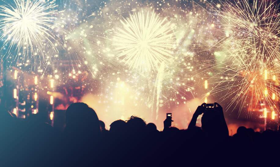 Neujahrskonzept - jubelnde Menge und Feuerwerk im Hintergrund | © gettyimages.com/8213erika