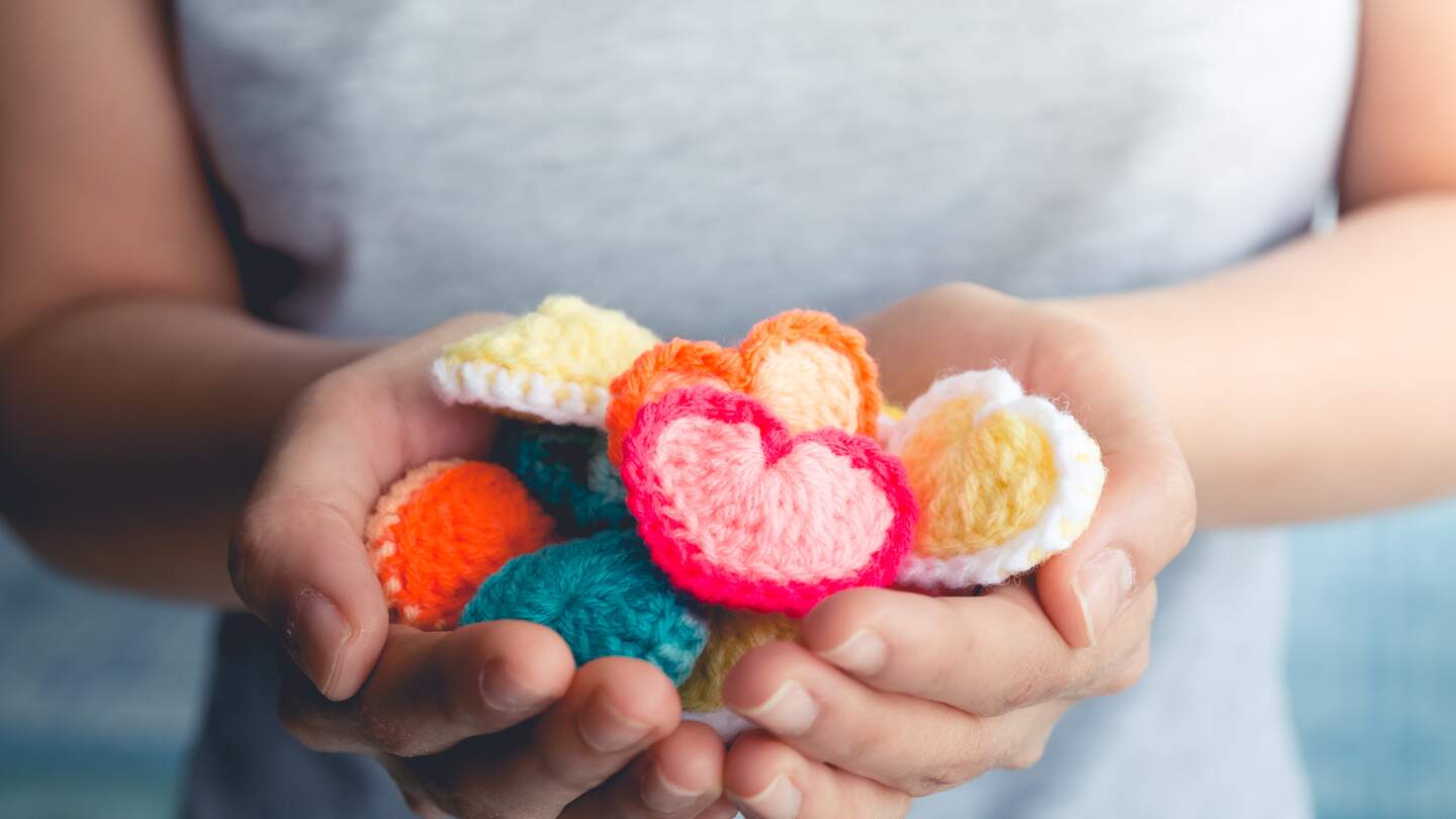 haende einer Frau, die gestrickte kleine bunte Herzen haelt | © gettyimages.com/Karimpard