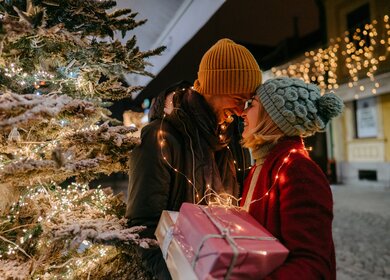 Foto eines romantischen Paares mit Weihnachtsgeschenken im Freien | © Gettyimages.com/AleksandarNakic