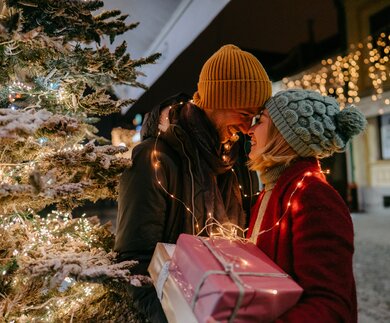 Foto eines romantischen Paares mit Weihnachtsgeschenken im Freien | © Gettyimages.com/AleksandarNakic