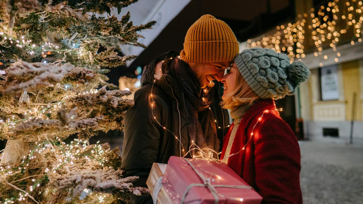 Foto eines romantischen Paares mit Weihnachtsgeschenken im Freien | © Gettyimages.com/AleksandarNakic