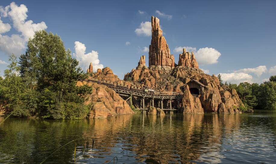 Die Attraktion Big Thunder Mountain. Im Vordergrund ein Gewaesser. | © Disney