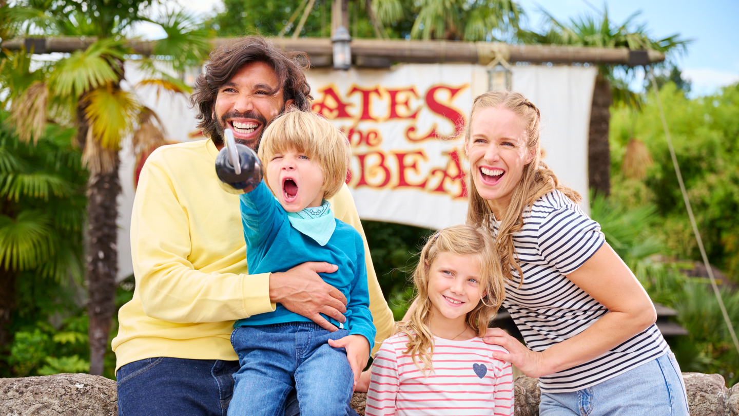 Frau, Mann und zwei Kinder vor dem Eingang der Attraktion Pirates of the Caribbean in Disneyland® Park | © Disney