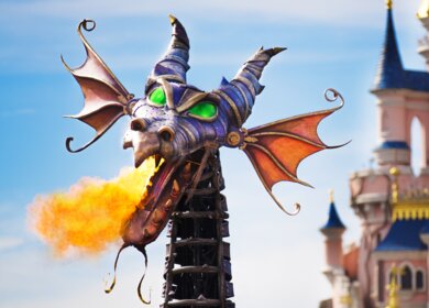 Paradewagen Maleficent in Form eines Drachen der Feuerspukt waehrend der Parade Disney Stars on Parade mit dem Schloss von Disneyland Park im Hintergrund | © Disney