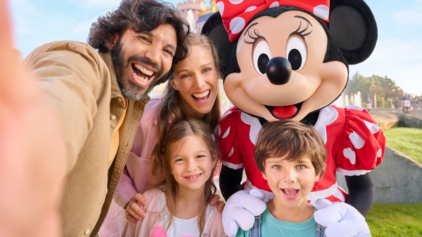 Minnie Maus und eine Familie mit zwei Kindern vor dem Sleeping Beauty Castle in Disneyland® Park | © Disney