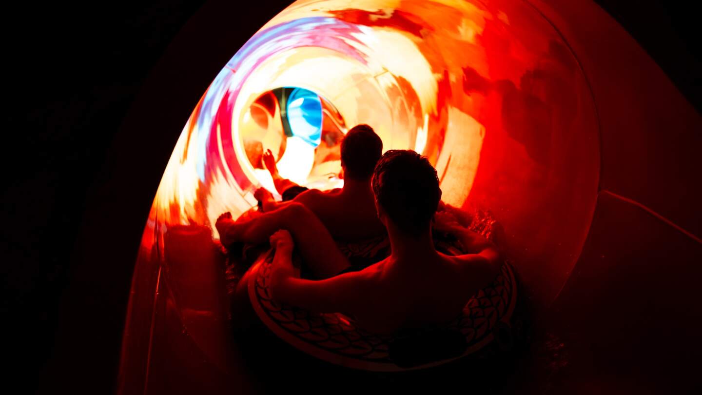 Zwei junge Maenner rauschen im 2er-Reifen durch die rote Rutsche Hugin | © Europa-Park