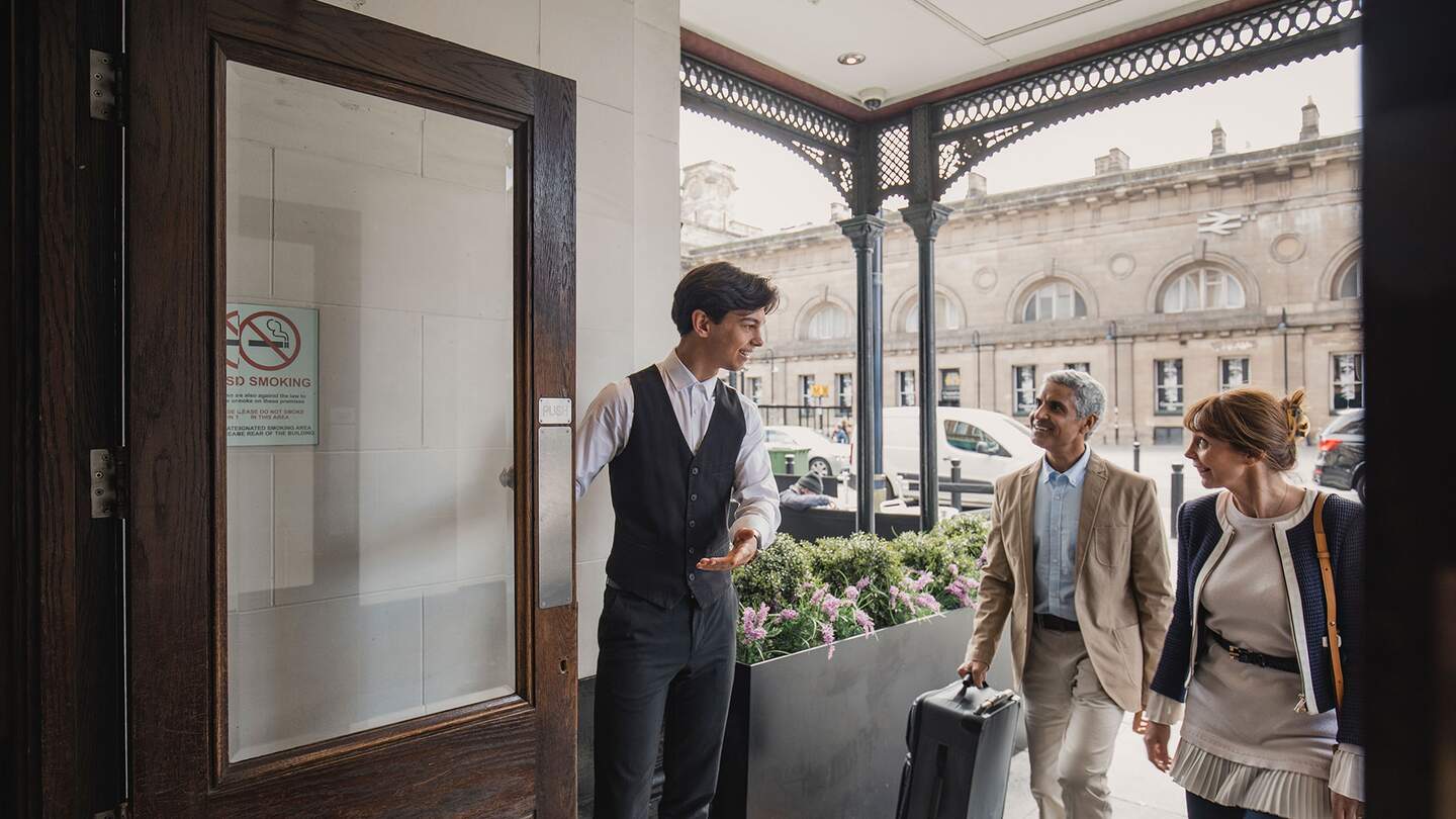Der Portier des Hotels empfaengt ein älteres Paar fuer einen Wochenendtrip | © Gettyimages.com/SolStock