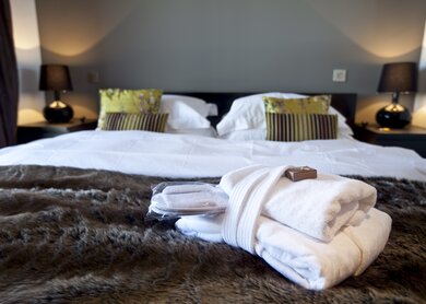 Modernes Hotelzimmer mit Kingsize-Bett, auf dem Handtuecher liegen | © Gettyimages.com/WILLSIE
