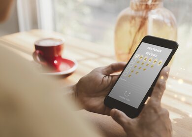 Frauen Hand halten Smartphone wählen Sie das 5-Sterne-Symbol, um Zufriedenheit im Service zu geben | © Gettyimages.com/aogreatkim