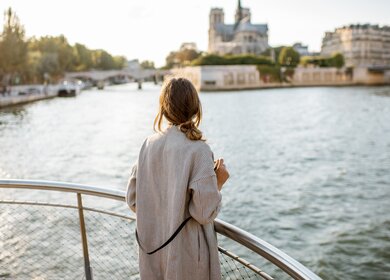 Frau geniesst den Landschaftsblick auf die Stadt Paris vom Boot aus | © Gettyimages.com/RossHelen