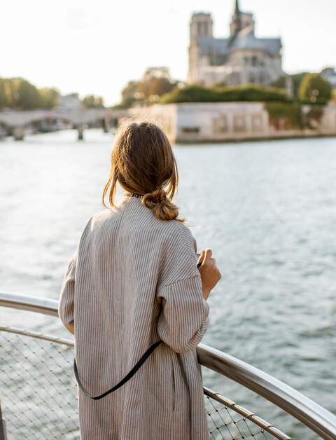 Frau geniesst den Landschaftsblick auf die Stadt Paris vom Boot aus | © Gettyimages.com/RossHelen