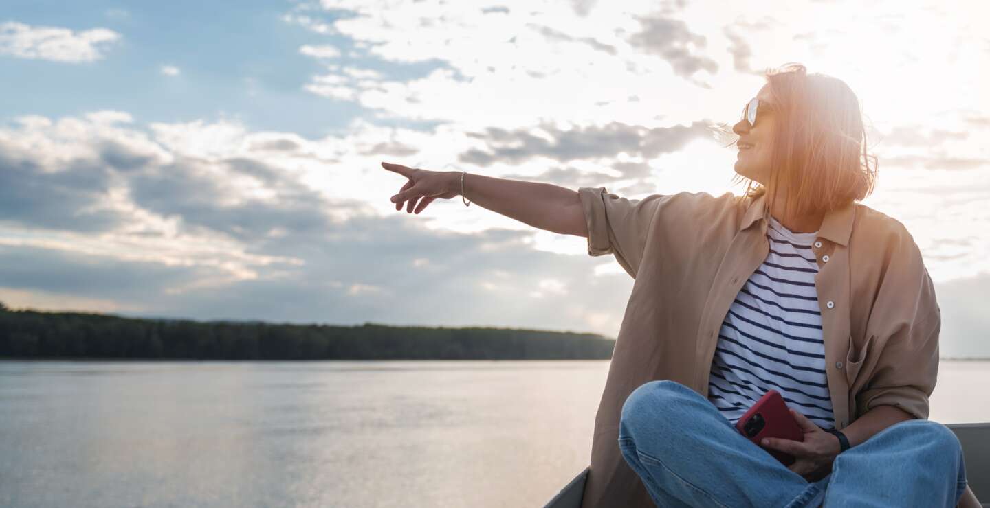 Eine Frau zeigt von einem Boot in die Breitengrade | © Gettyimages.com/Olezzo