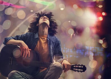Junger Mann spielt Gitarre vor kuenstlerischem Hintergrund | © Gettyimages.com/seb_ra 