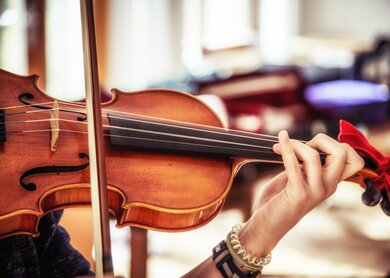 Nah aufnahme von einer Violine, die von einem Musiker gespielt wird | © Gettyimages.com/suteishi