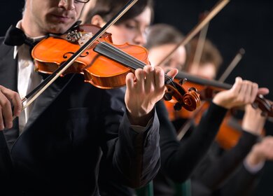 Geiger treten auf der Buehne vor dunklem Hintergrund mit einem Orchester auf | © Gettyimages.com/cyano66