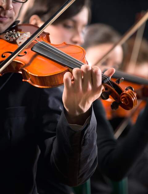Geiger treten auf der Buehne vor dunklem Hintergrund mit einem Orchester auf | © Gettyimages.com/cyano66