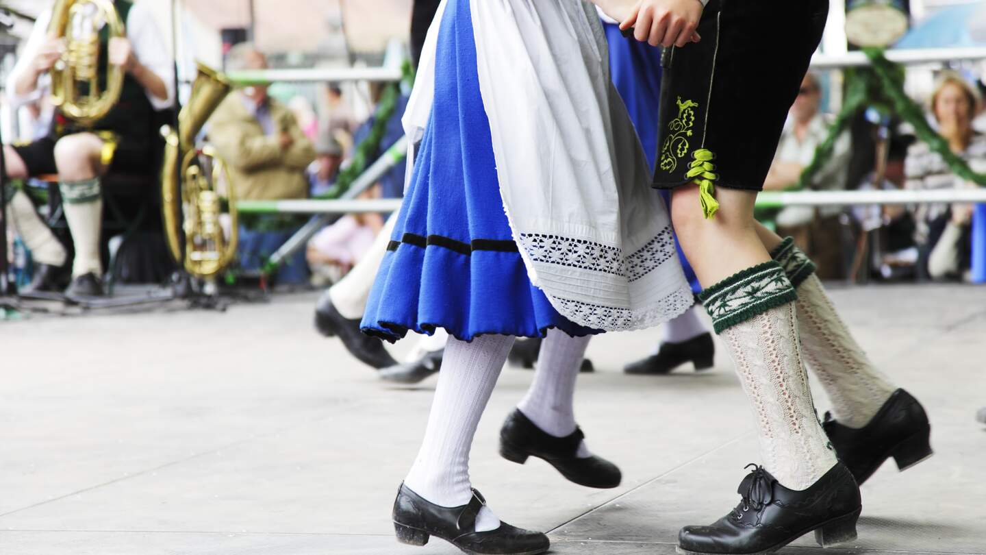 Junges bayerisches Paar in Lederhose und Dirndl tanzt zu typisch bayerischer Blasmusik | © Gettyimages.com/sebastian-julian