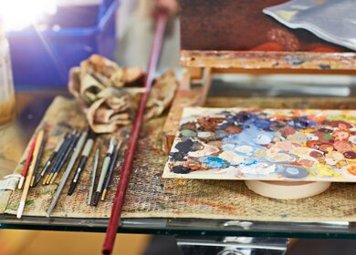 Aufnahme einer Farbpalette und Pinseln auf einem Tisch  | © Gettyimages.com/Goodboy Picture Company