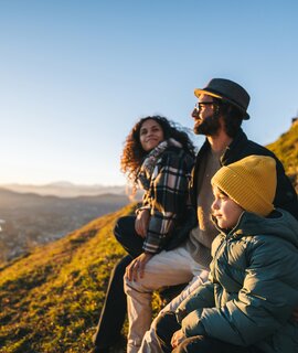 Familie in der Natur genießen den Sonnenuntergang in den Bergen | © Gettyimages.com/AscentXmedia