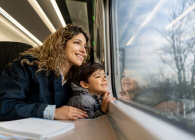 Mutter schaut mit ihrem Kind aus dem Fenster eines Zuges | © Gettyimages.com/Hispanolistic