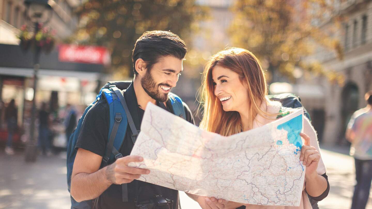 Paar Backpacker, die die Karte in der Stadt ueberpruefen | © Gettyimages.com/danchooalex