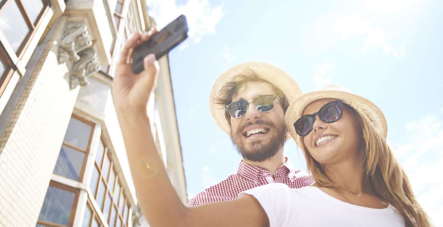 Glückliches Mädchen, das Selfie mit ihrem Freund in der Nähe macht | © Gettyimages.com/shironosov