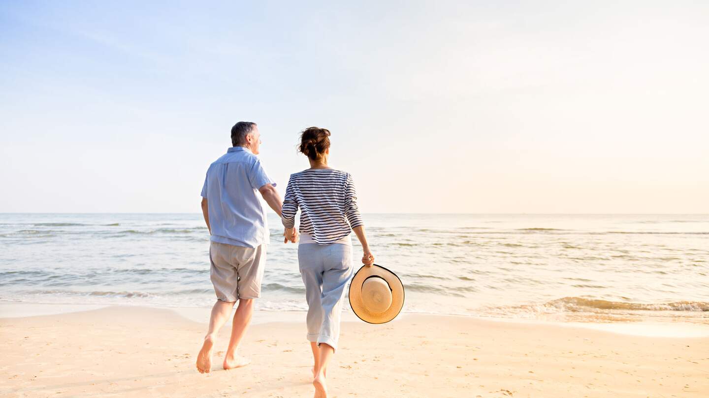 Aktives Seniorenpaar, das am Strand spazieren geht | © Gettyimages.com/FredFroese