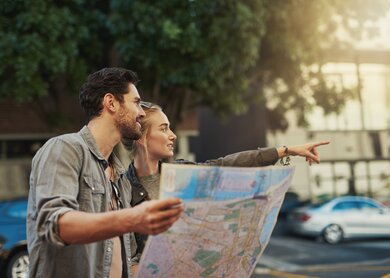 Aufnahme eines jungen Paares mit einer Karte bei der Erkundung der Stadt | © Gettyimages.com/PeopleImages