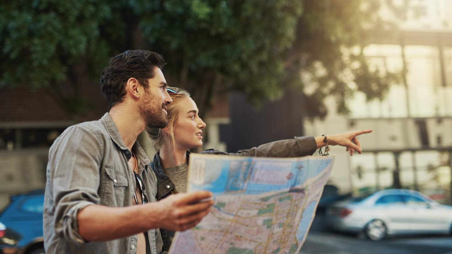 Aufnahme eines jungen Paares mit einer Karte bei der Erkundung der Stadt | © Gettyimages.com/PeopleImages