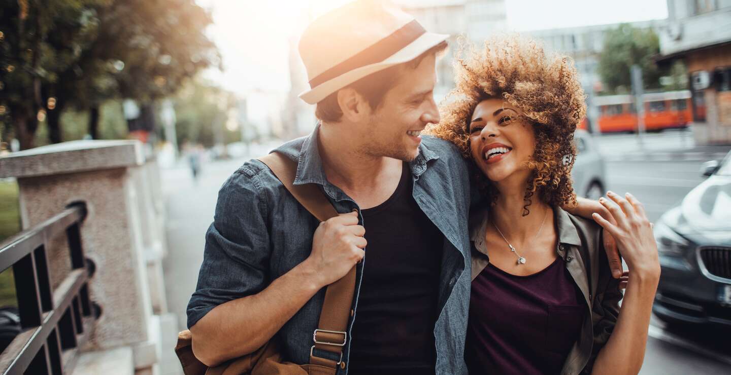 Nahaufnahme eines glücklichen jungen Paares, das Arm in Arm das Stadtleben genießt | © Gettyimages.com/Geber86