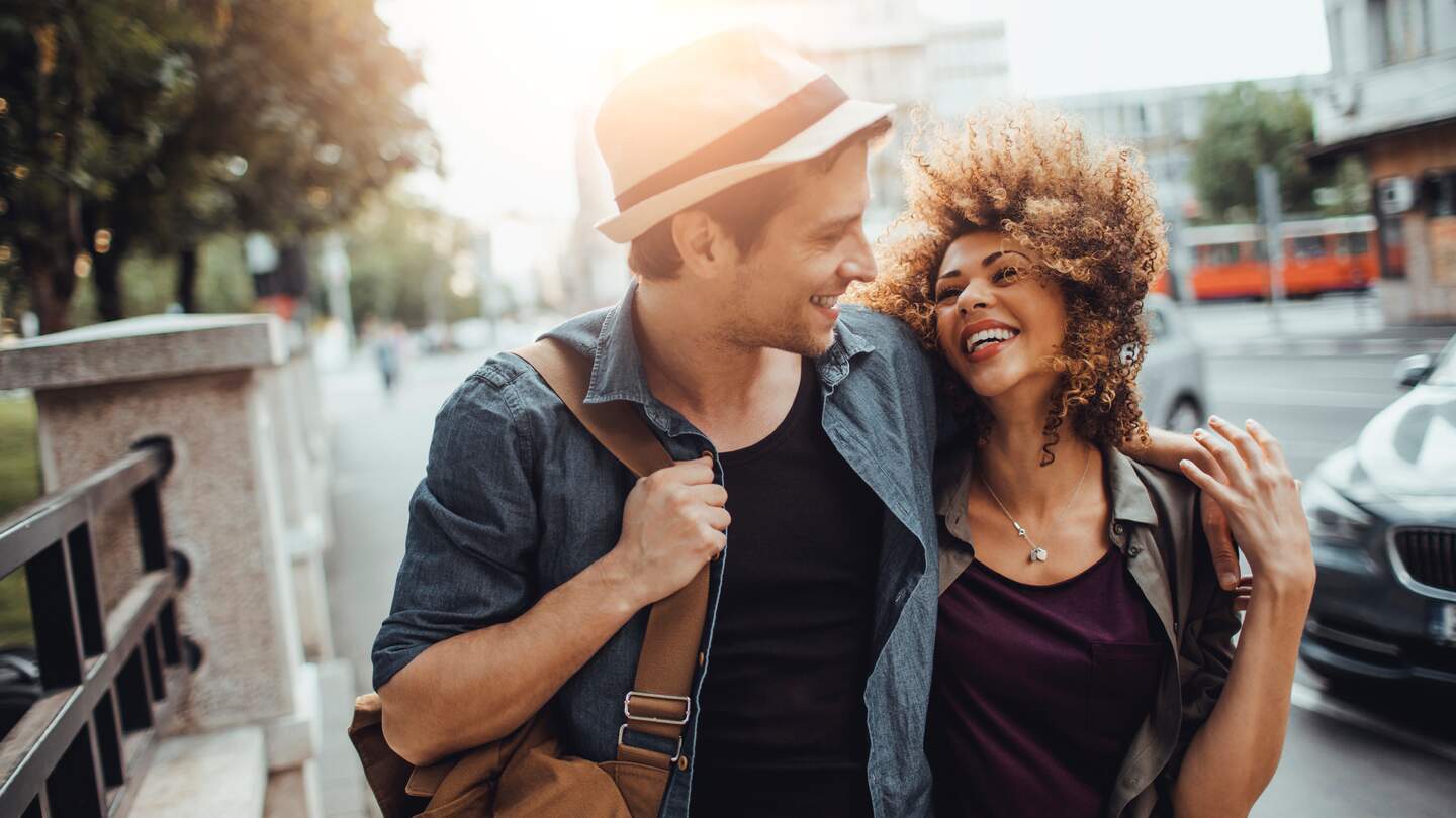 Nahaufnahme eines glücklichen jungen Paares, das Arm in Arm das Stadtleben genießt | © Gettyimages.com/Geber86
