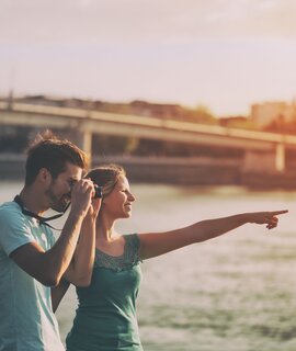 Paar in einer Stadt im Sommer. Mann macht Foto mit einer Kamera. | © Gettyimages.com/Ines Bazdar
