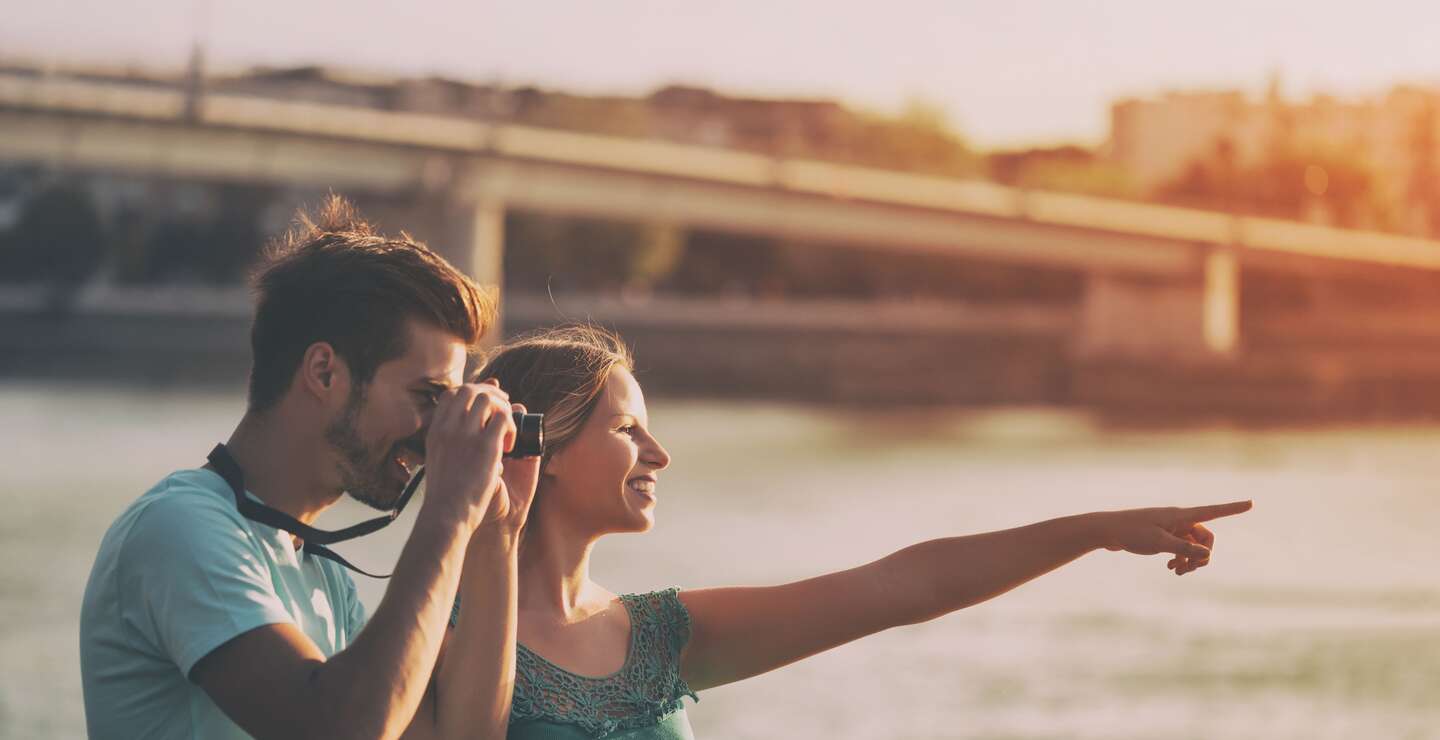 Paar in einer Stadt im Sommer. Mann macht Foto mit einer Kamera. | © Gettyimages.com/Ines Bazdar