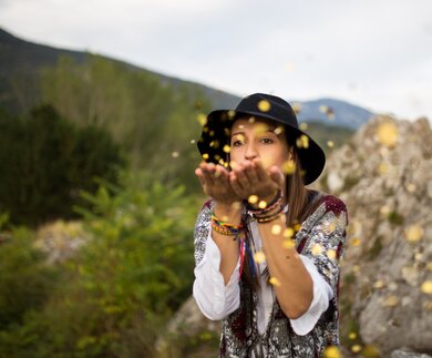 EIne Frau entspannt sich auf dem Berg und blaest Konfetti | © Gettyimages.com/South agency