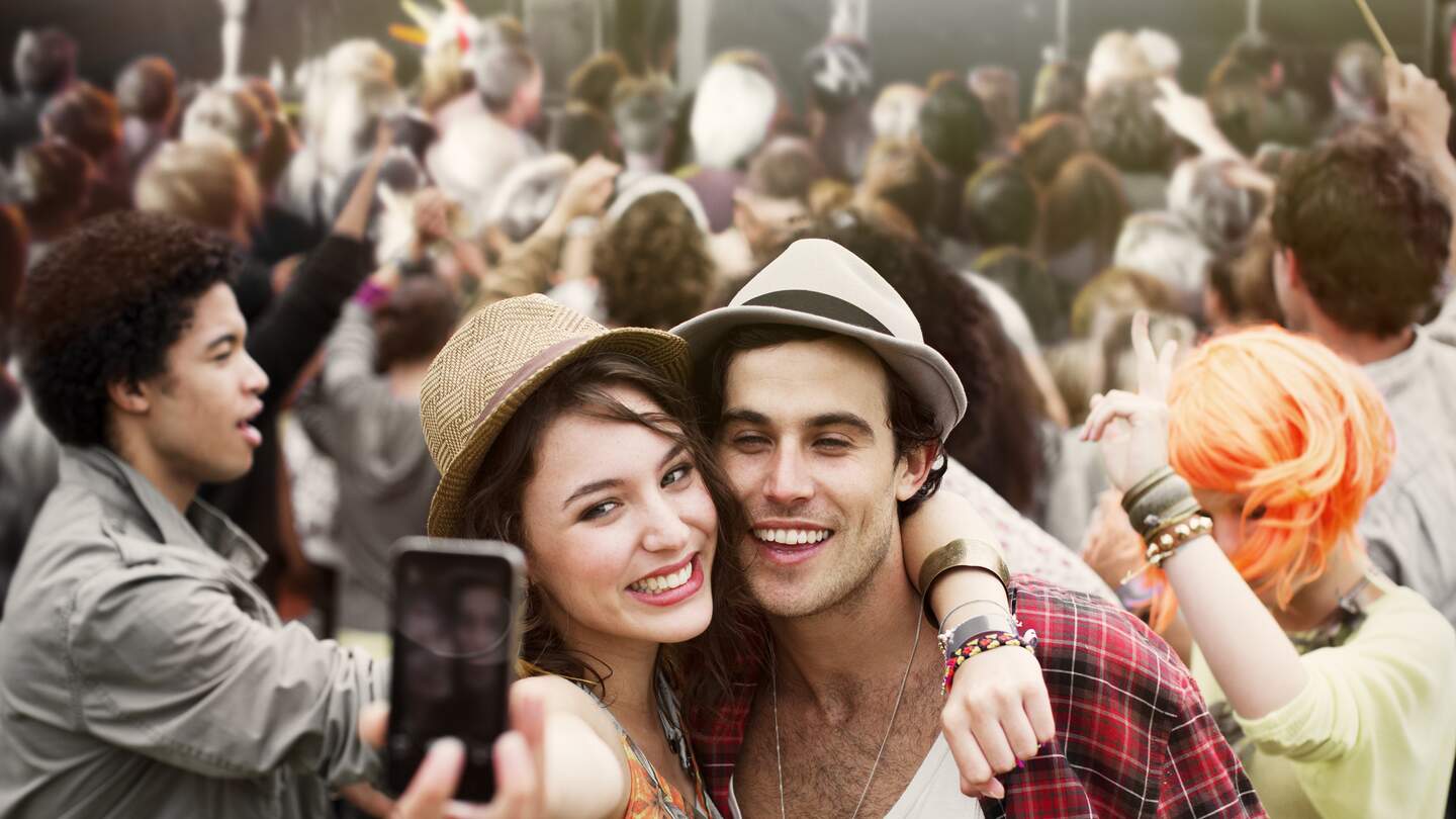 Glueckliches Paar macht ein Selfie auf einem Festival. | © Gettyimages.com/Paul Bradbury